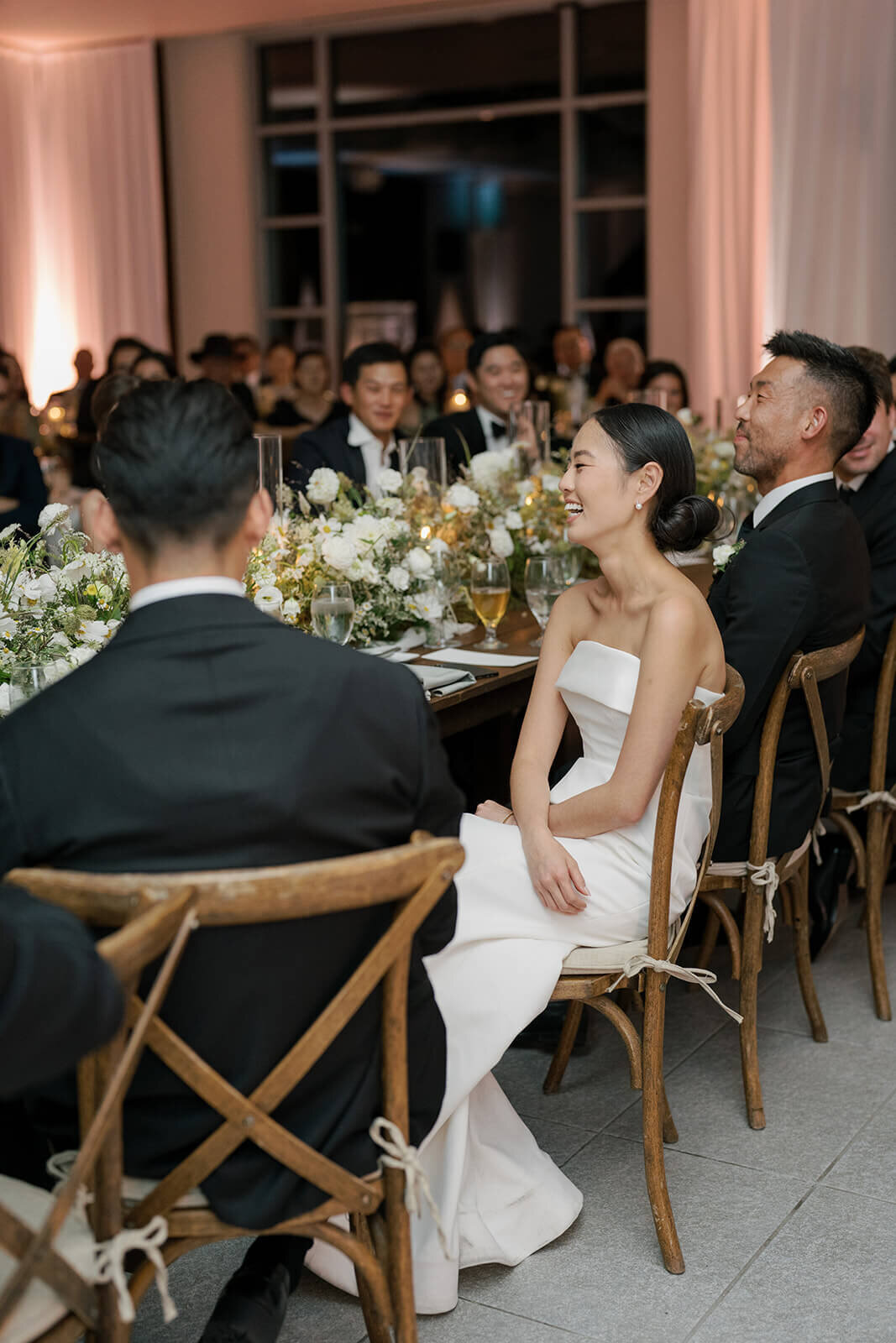 Bride sits among her family and friends at the head table of her Aspen Meadows Resort wedding reception.