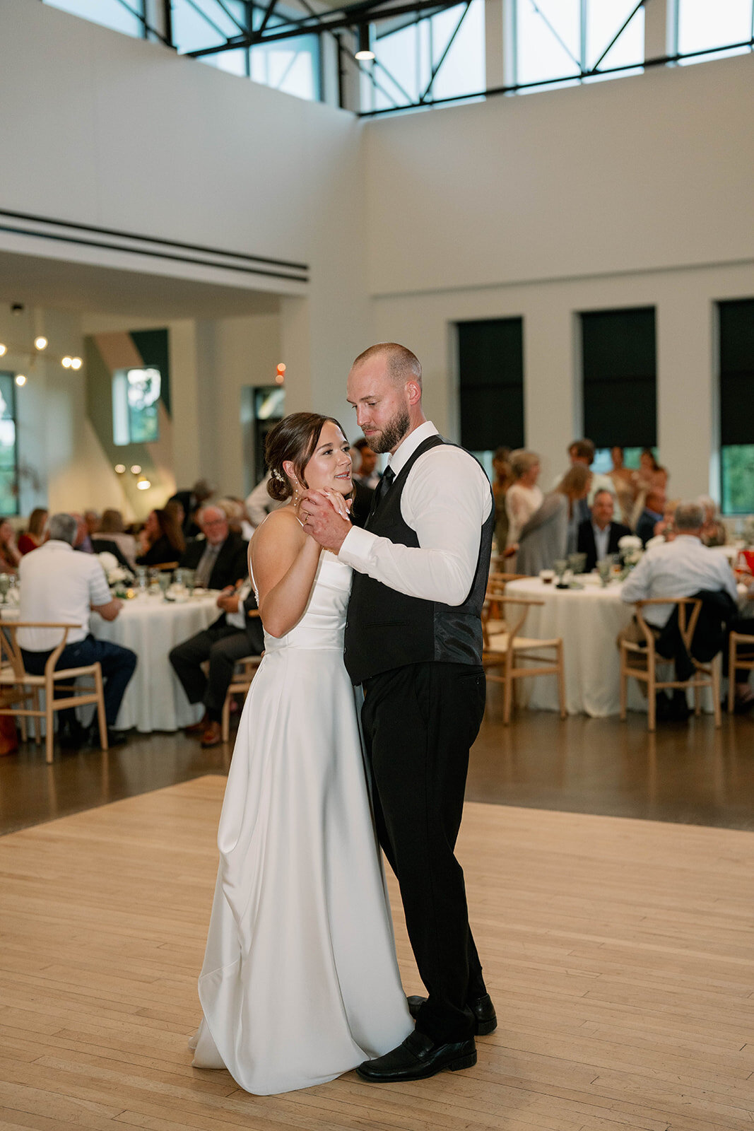 Bride and groom dancing during their first dance surrounded by guests inside Leona Road Wedding Venue in Grand Rapids, MI.
