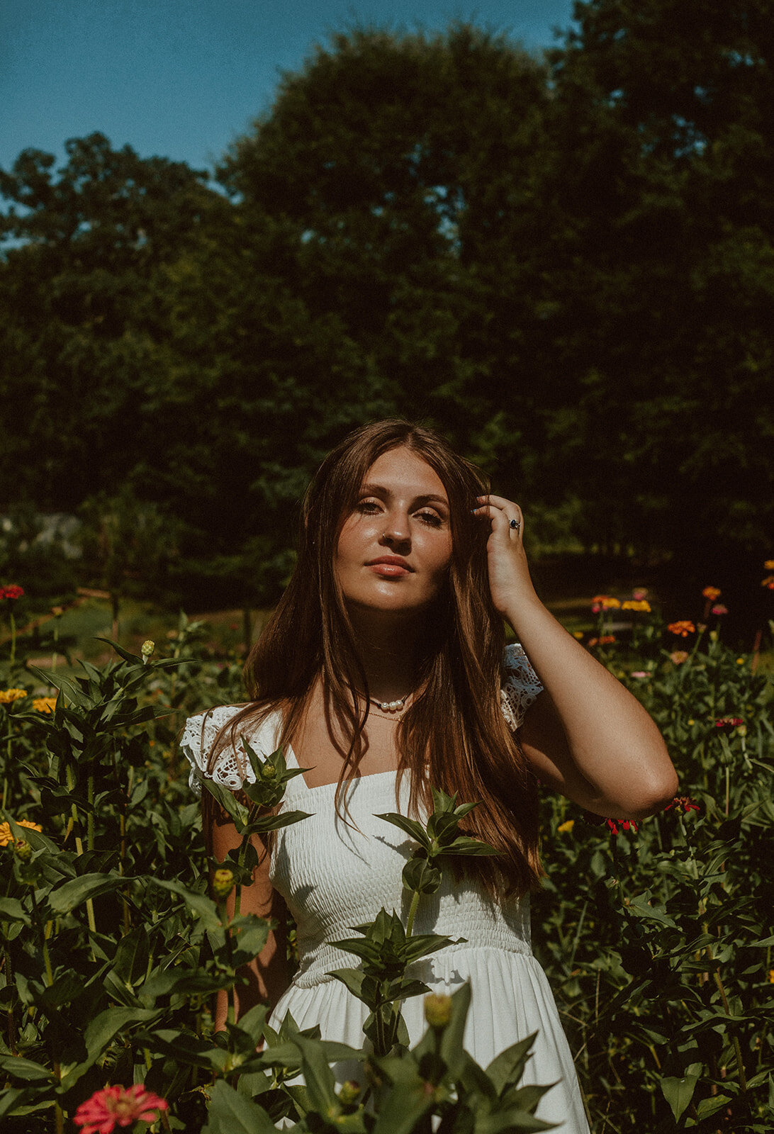 highschool female senior in white dress in field of flowers