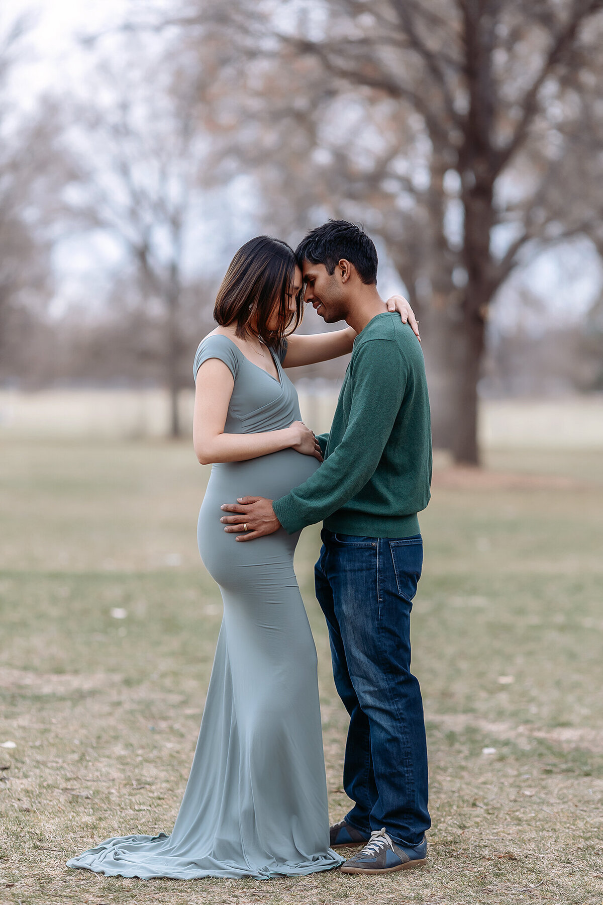 couple hugging as mama touches her pregnant belly for their maternity photos in denver, colorado