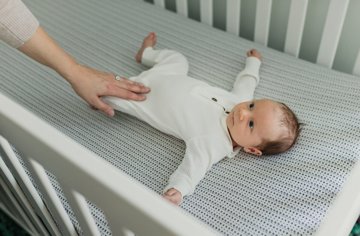 Infant photographer capturing a newborn baby sleeping in crib