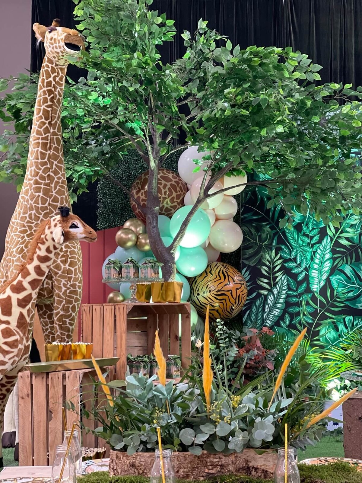 Jungle children's party with toy giraffe's and big tress and balloons