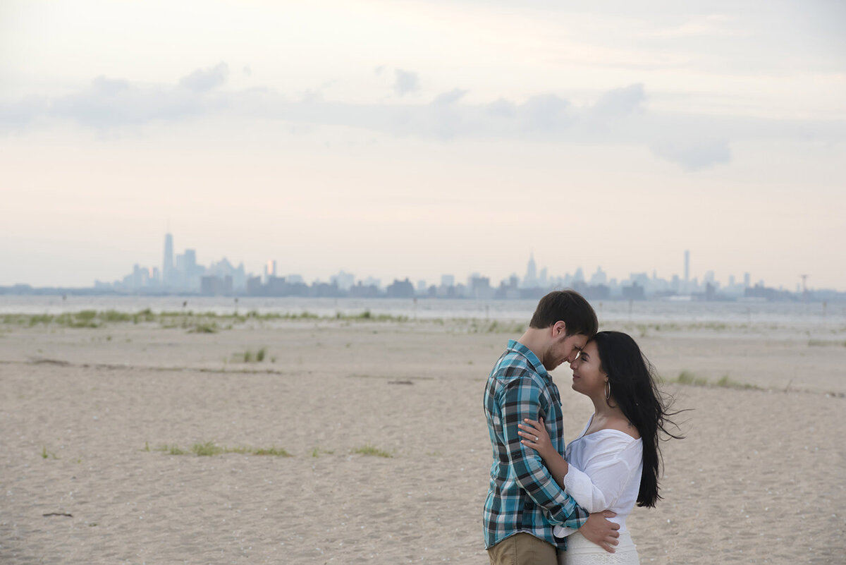 A couple standing forehead to forehead on a beach 