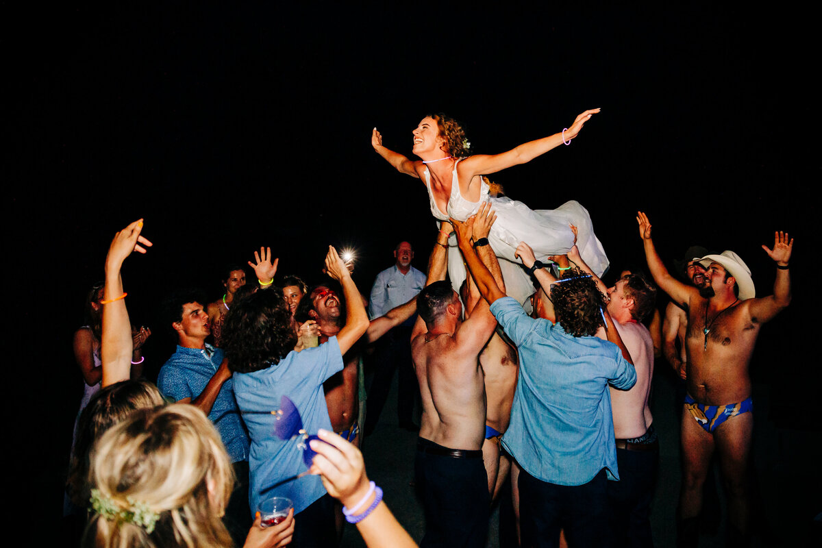 Bride crowd surfing during wedding reception at Miles Park Band Shell in Livingston, MT