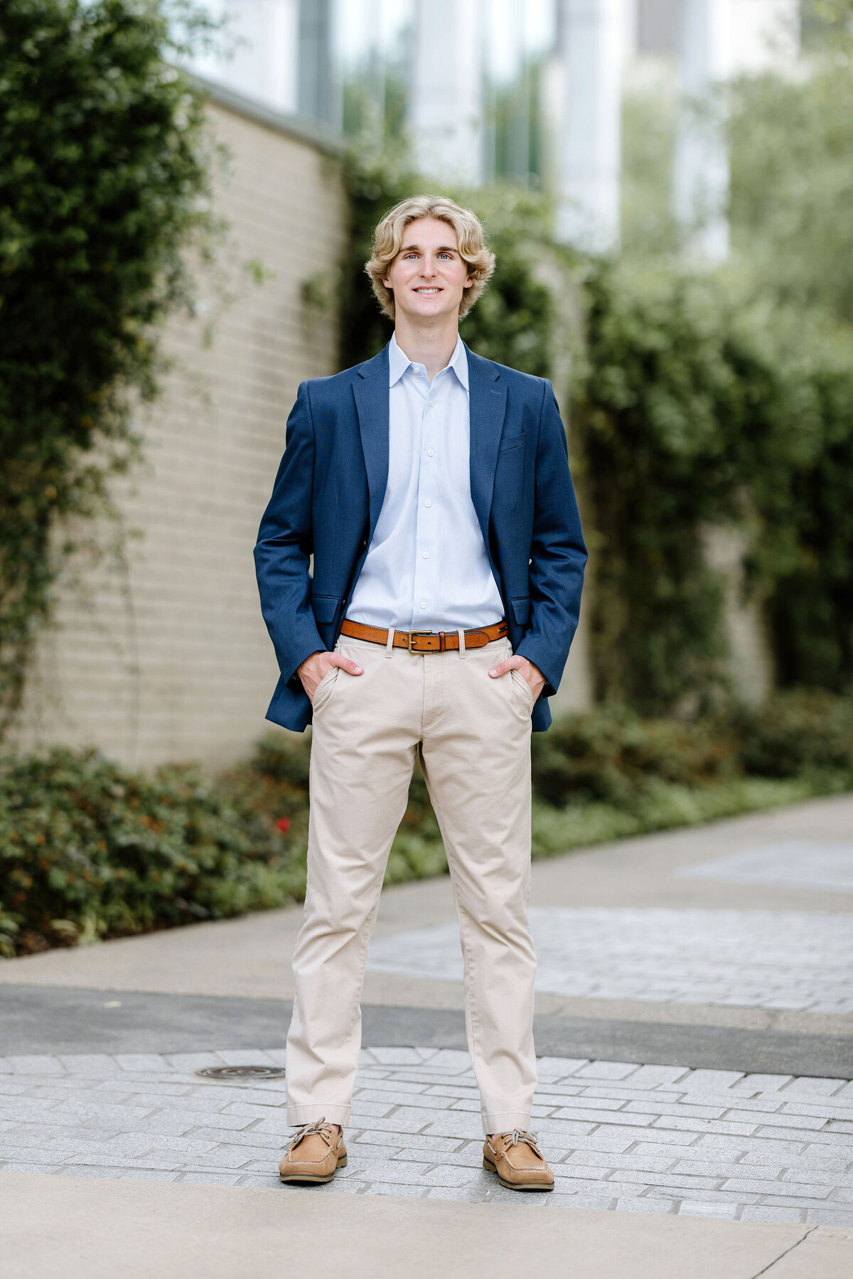 senior picture of blonde male in navy suit coat, light blue shirt, and dress pants