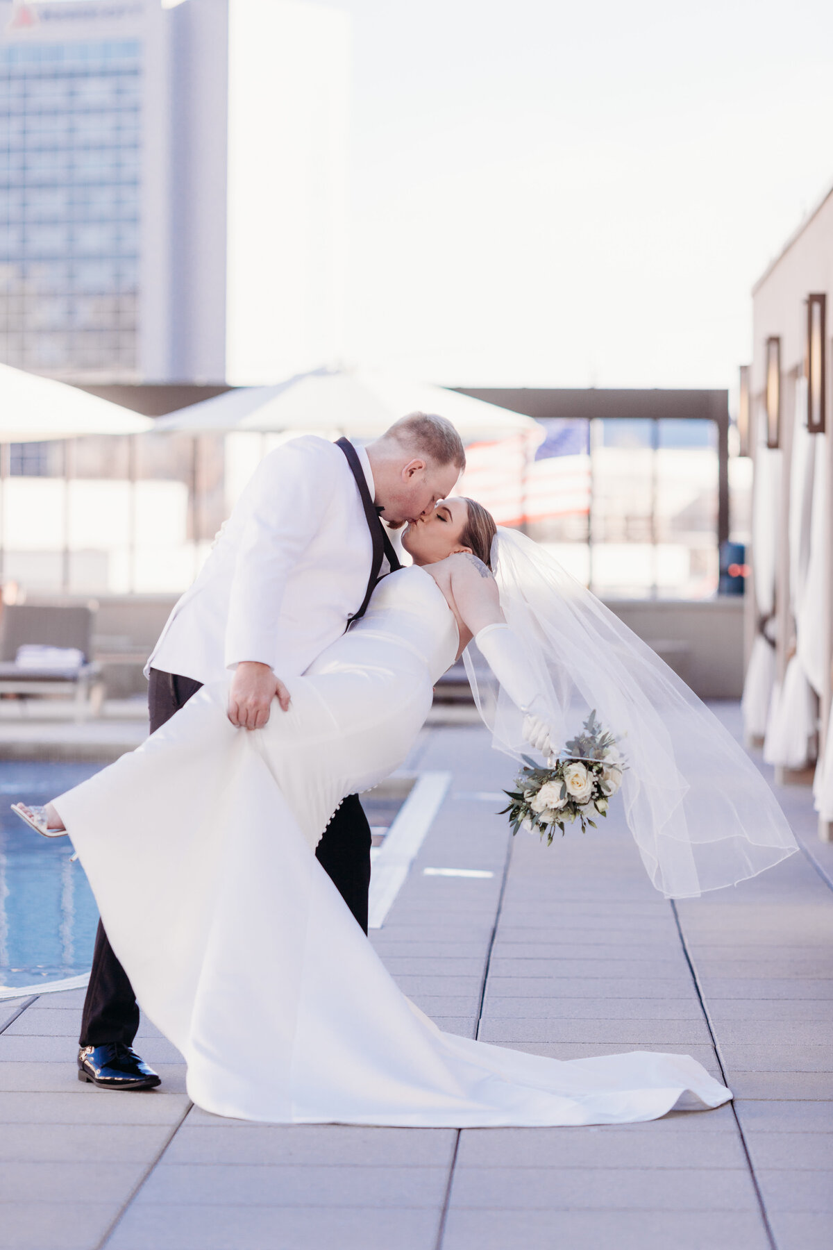 groom dips his wife and kisses her by the rooftop pool of the westin