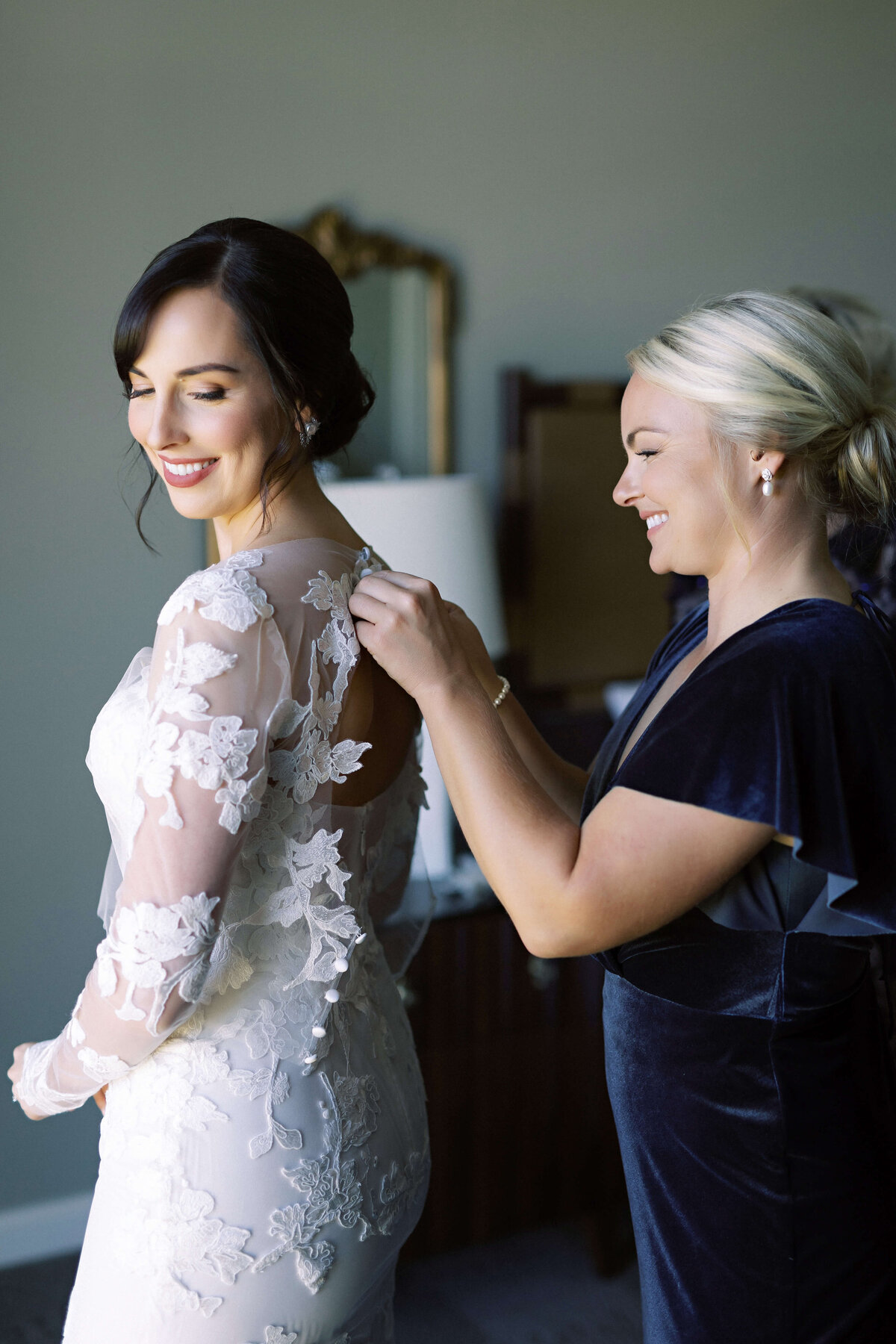 bride putting on her dress by Monique Lhuillier