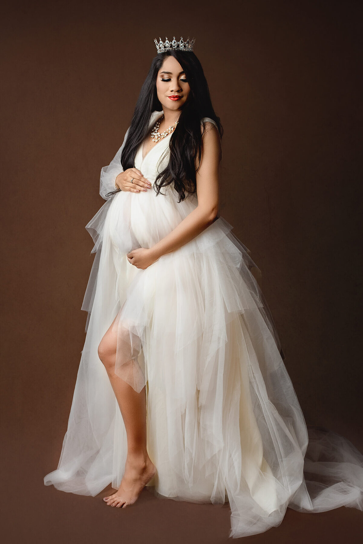 expecting mother wears a crown and beautiful cream tulle dress for her maternity shoot in Hamilton, ON
