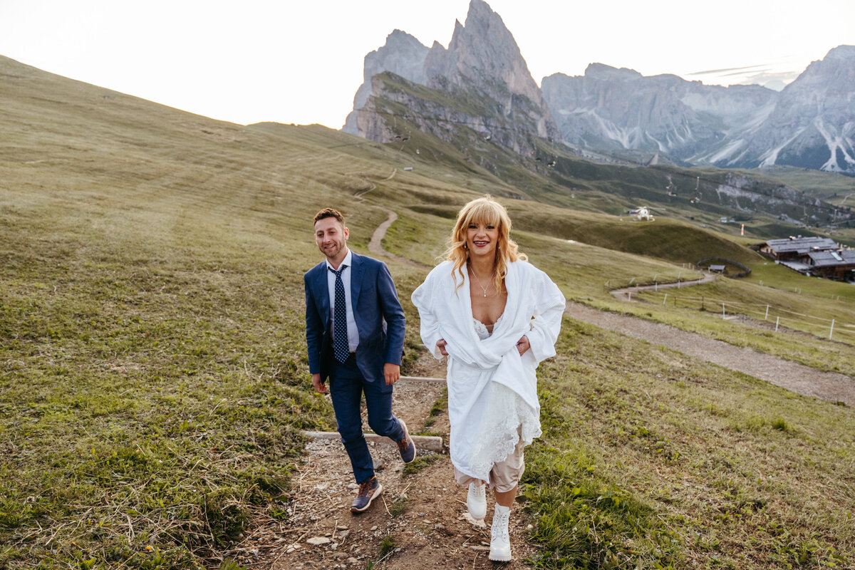 Bride and groom walking through mountain meadow golden hour