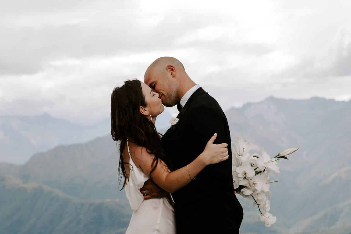 The Lovers Elopement Co - wedding couple kiss on top of mountain, heli wedding