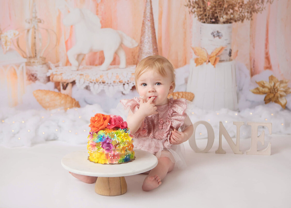 Baby licking her fingers enjoying her first birthday cake smash in Calabasas - - By Los Angeles Newborn Photographer