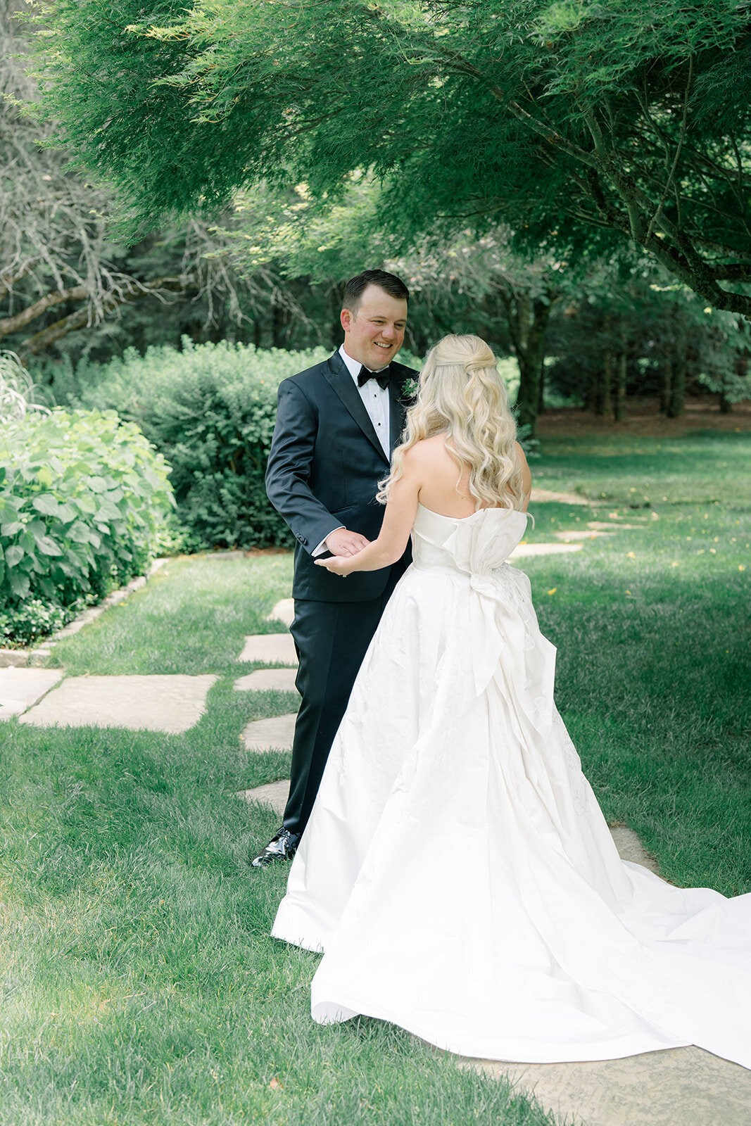 Bride and groom smiling and holding hands during emotional first look in the garden at Old Edwards Inn in Highlands, NC.