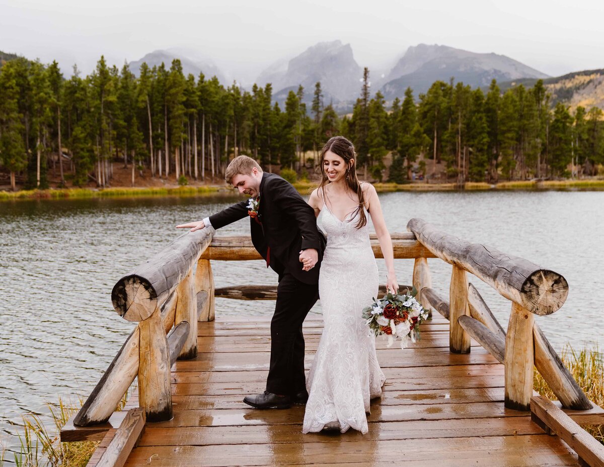 Couple walks hand in hand on the dock at Sprague Lake in Rocky Mountain National Park during their elopement