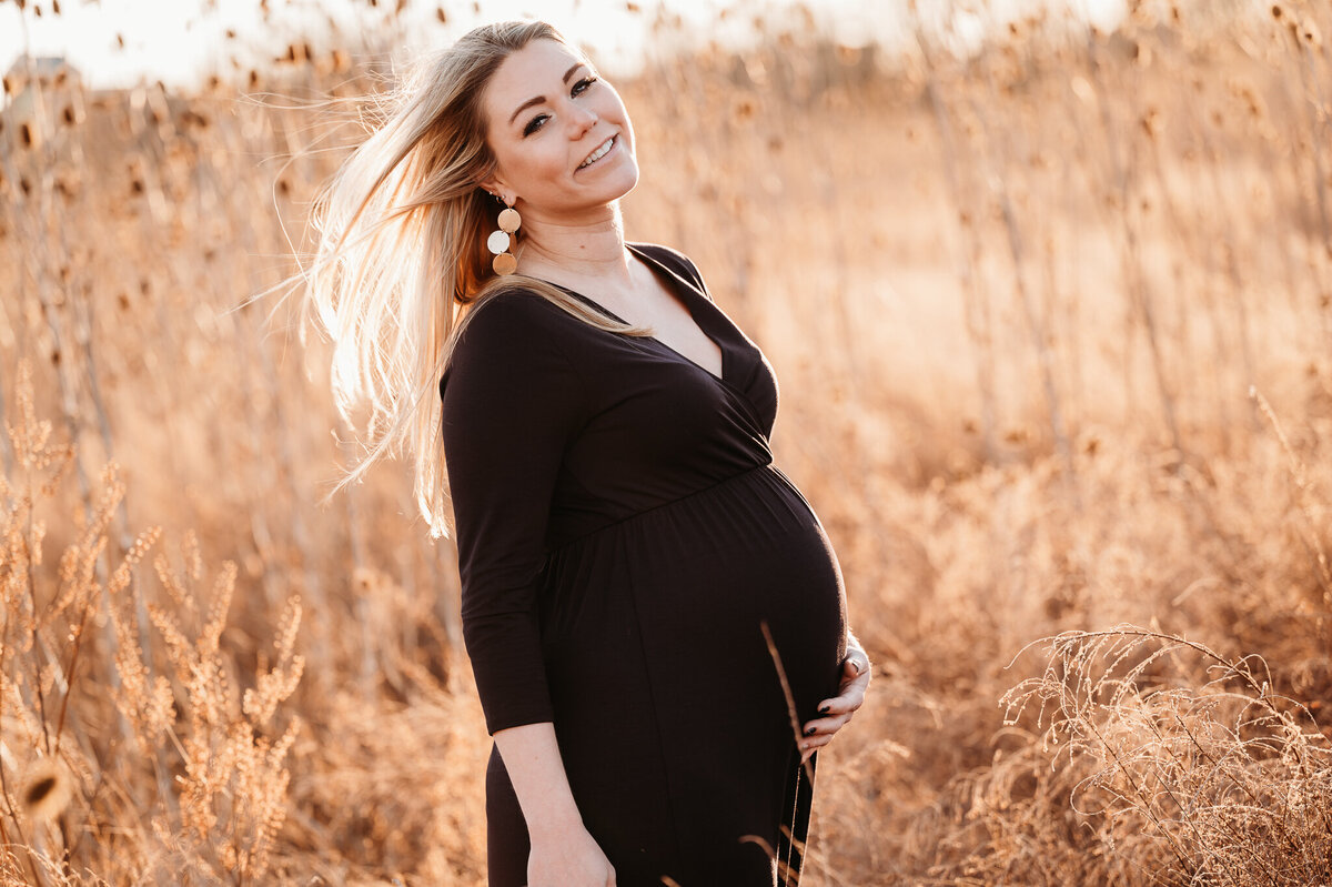 Pregnant beautiful young woman smiling outside during golden hour