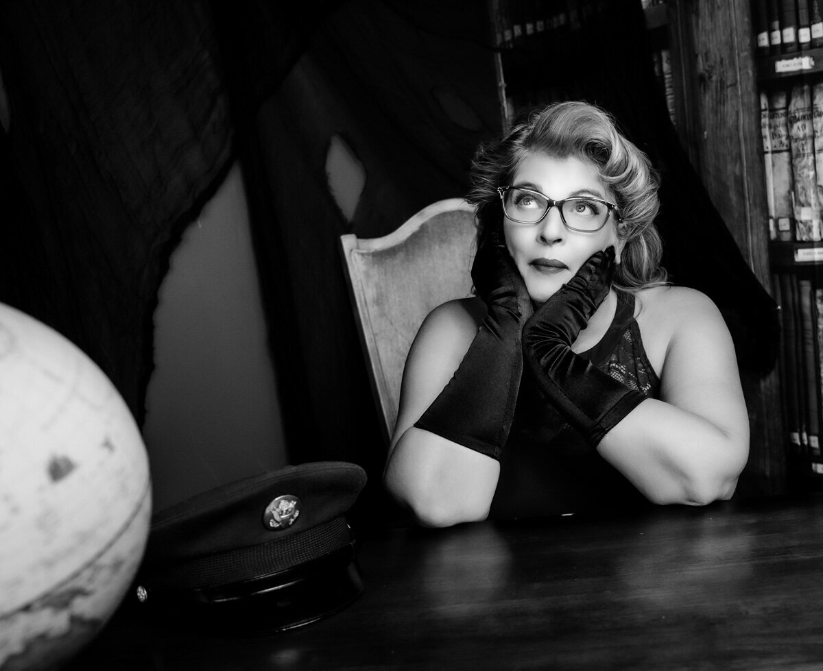Retro black and white photo of  woman  sitting at desk with world globe and wearing black gloves  in the Twin Cities