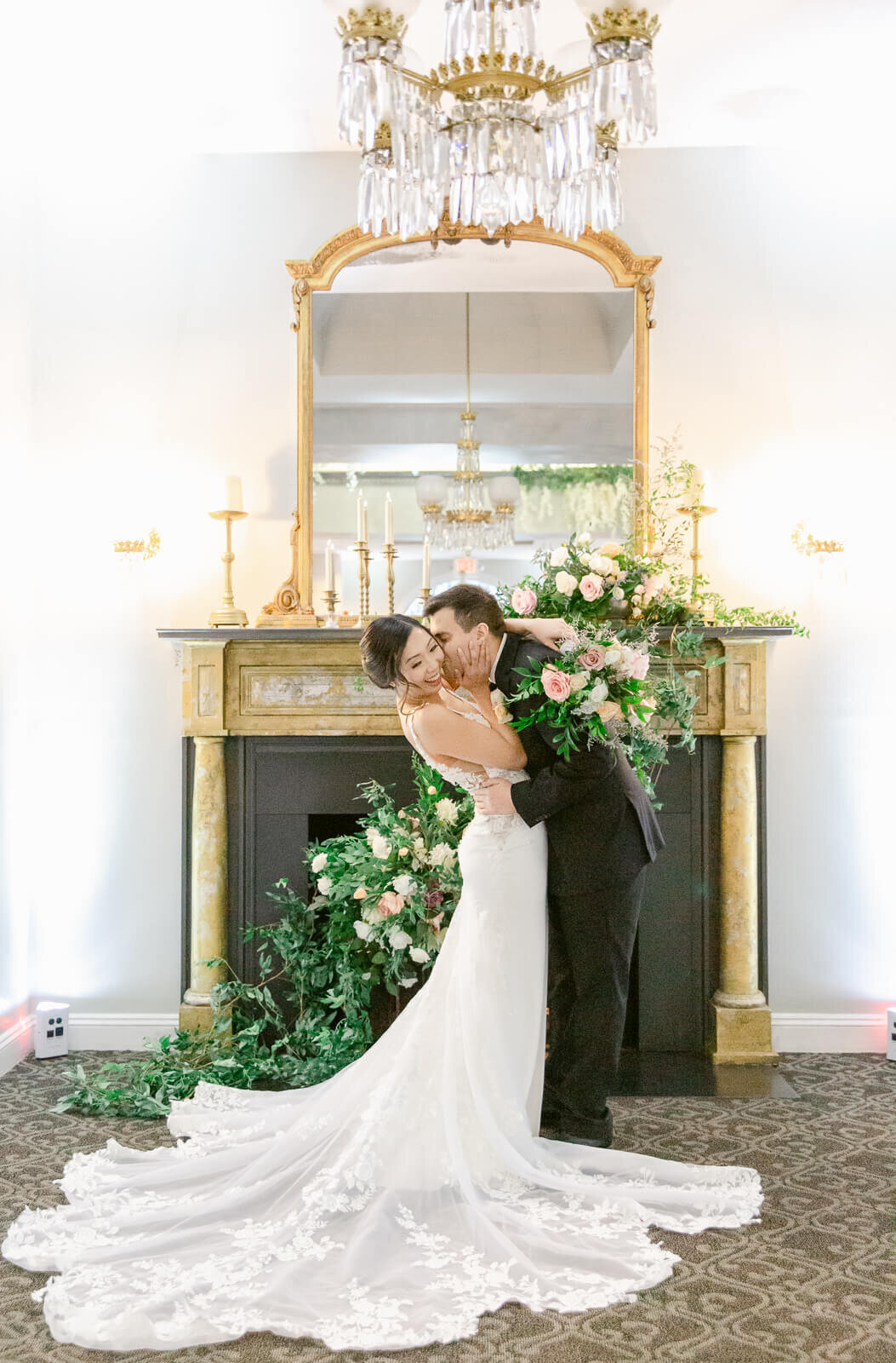 Groom kissing bride's cheek in front of the fireplace at Ceresville Mansion in Frederick, Maryland. Takne by Bethany Aubre Photography.