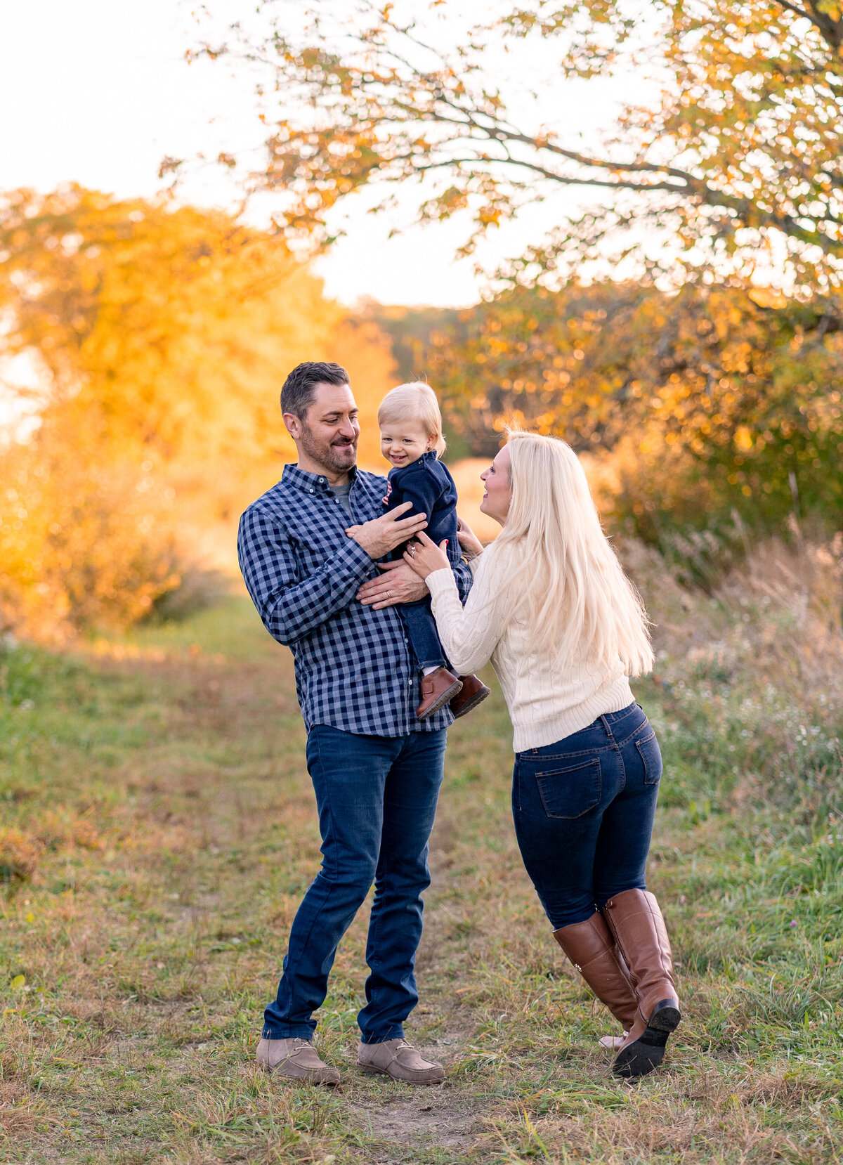 dad snuggling baby with mom running up to tickle baby at a Kensington Metropark in Milford Michigan
