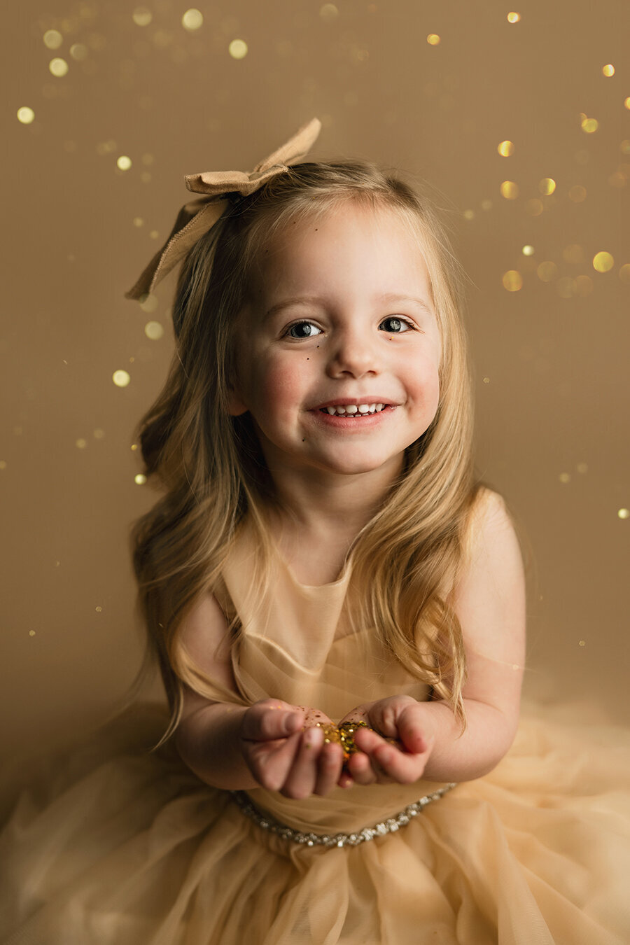 Adorable little girl holding glitter in her hands with a smile on her face