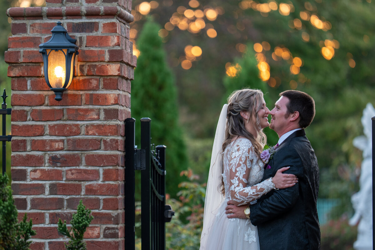 A wedding couple standing close smiling as they are about to kiss 