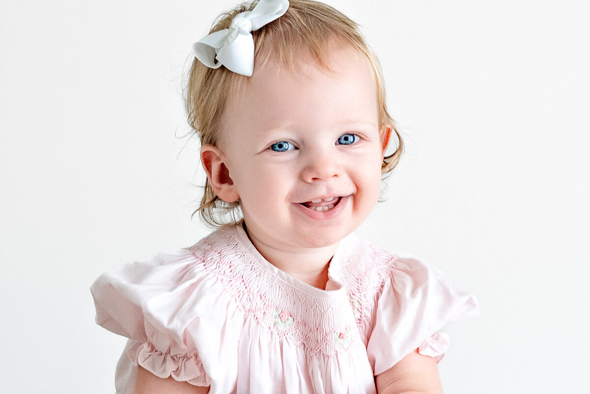 A baby girl with blue eyes  smiles during family photos in Huntsville