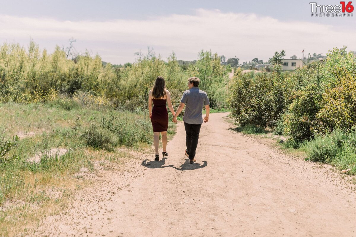 Engaged couple go for a walk holding hands on a Peters Canyon Regional Park trail