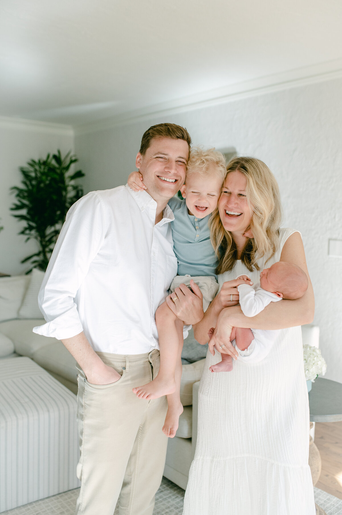 Photo of a family of 4 with toddler between mom and dad and baby in mom's arms