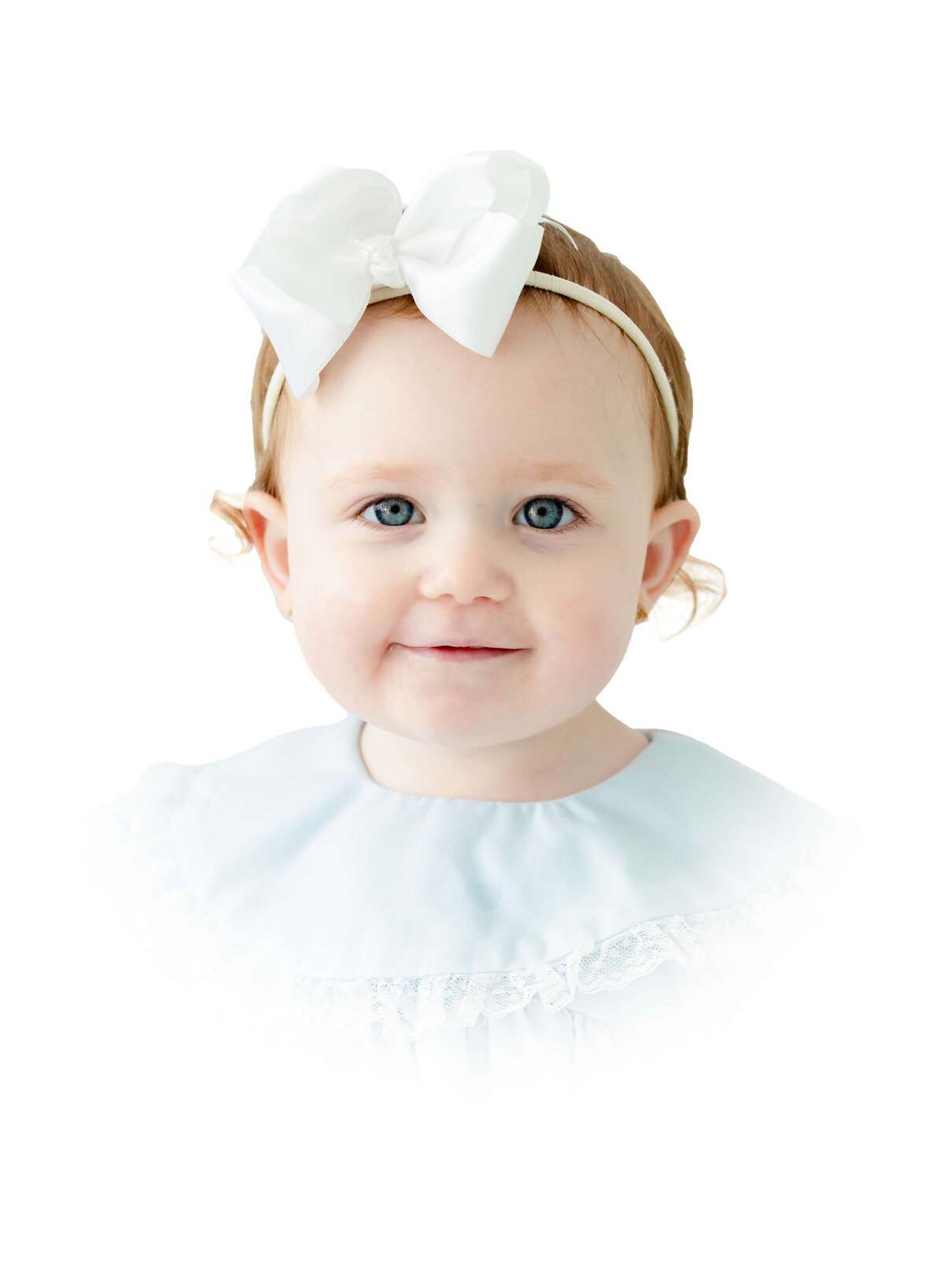 Toddler with white bow in heirloom outfit smiling at the camera posing for heirloom photography in Dothan Alabama Photography Studio