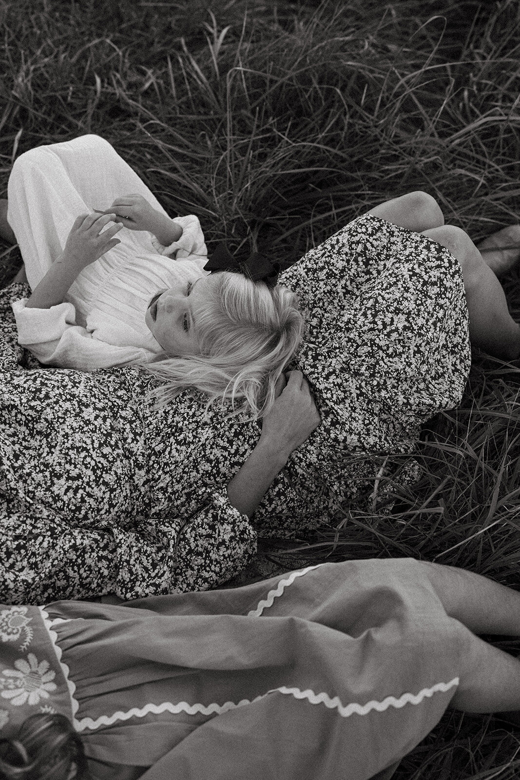 Little girl laying on her mother’s chest in a sunlit field during a heartfelt family photography session
