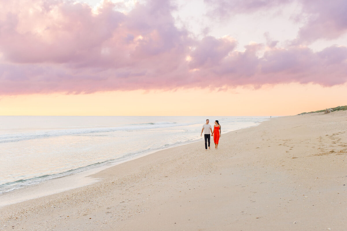 Couple walking along the shoreline at Cape Canaveral National Seashore at sunrise during their proposal  session