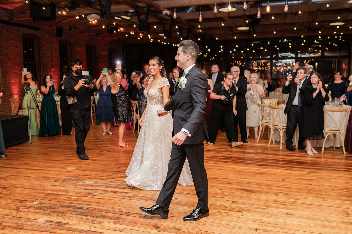 couple is all smiles as they enter their wedding reception