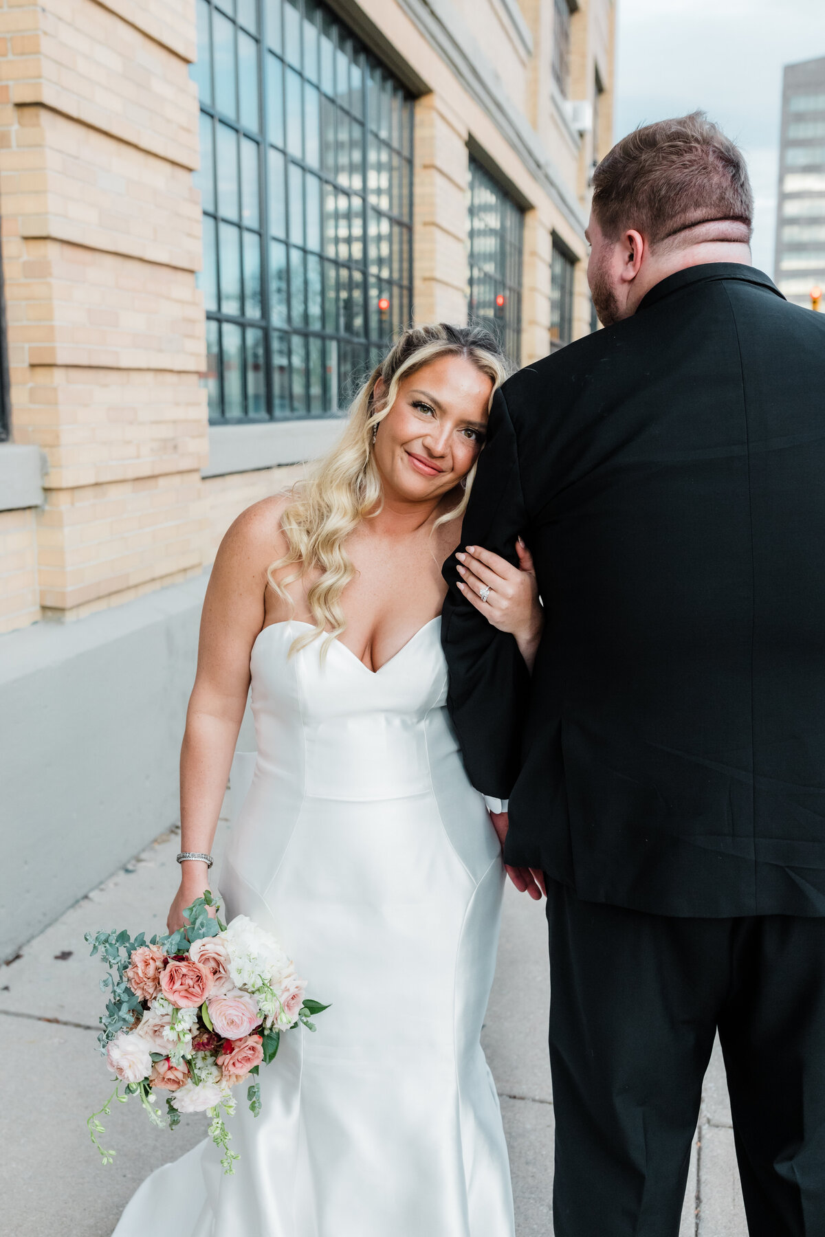 Bride and groom sharing a joyful moment outdoors by a modern building in downtown South Bend.