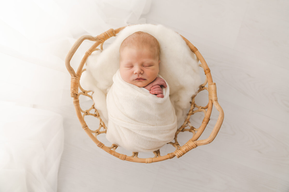 Baby swaddled in a basket, taken by Stickan Photography a Minneapolis Newborn Photographer