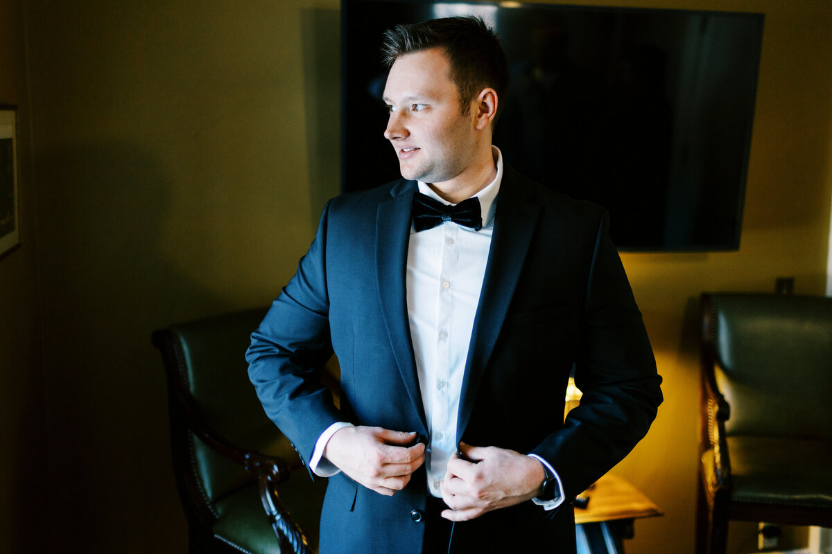 Groom buttoning his jacket