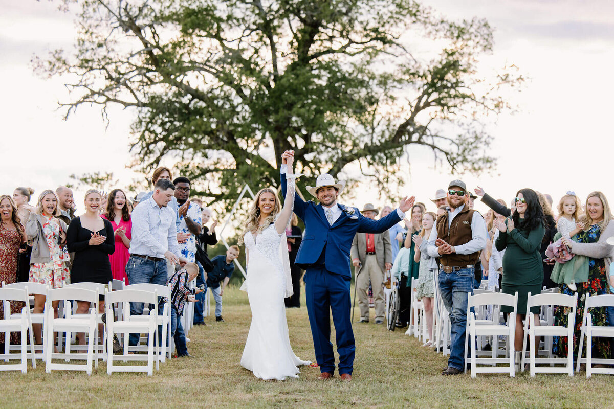 brinde and groom celebrating as they walk down aisle after wedding day ceremony as crowd cheers them on