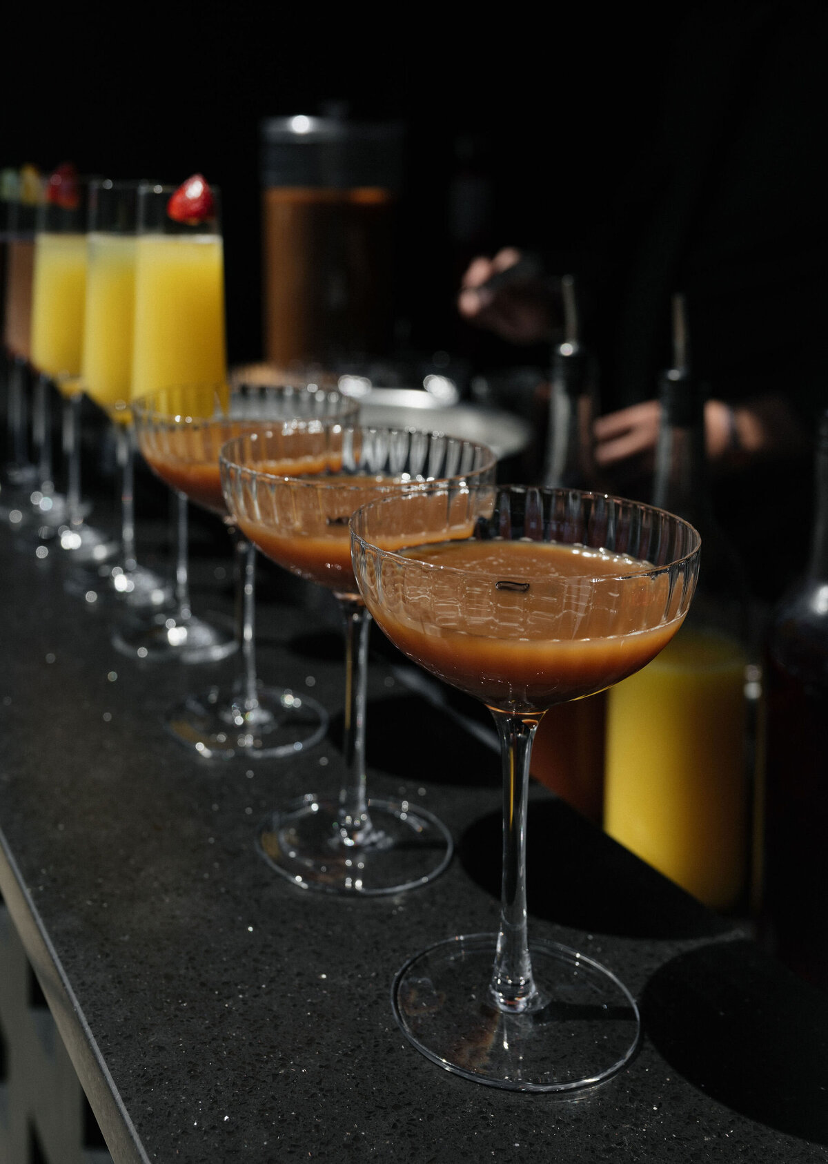 A row of coupe cocktails and mimosas along the bar