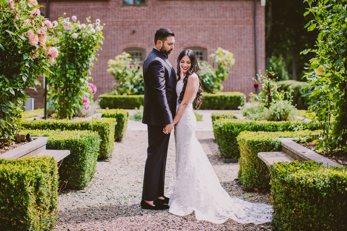 Indian bride and groom in a white dress share moment outside the ninety acres at natirar park