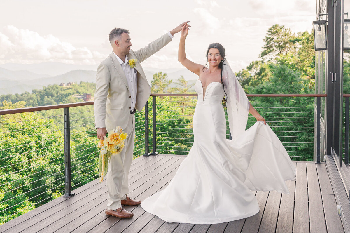 A happy bride and groom dancing on a porch at The Trillium overlooking the rich green mountains below them as they enjoying their Raleigh wedding photos by JoLynn Photography