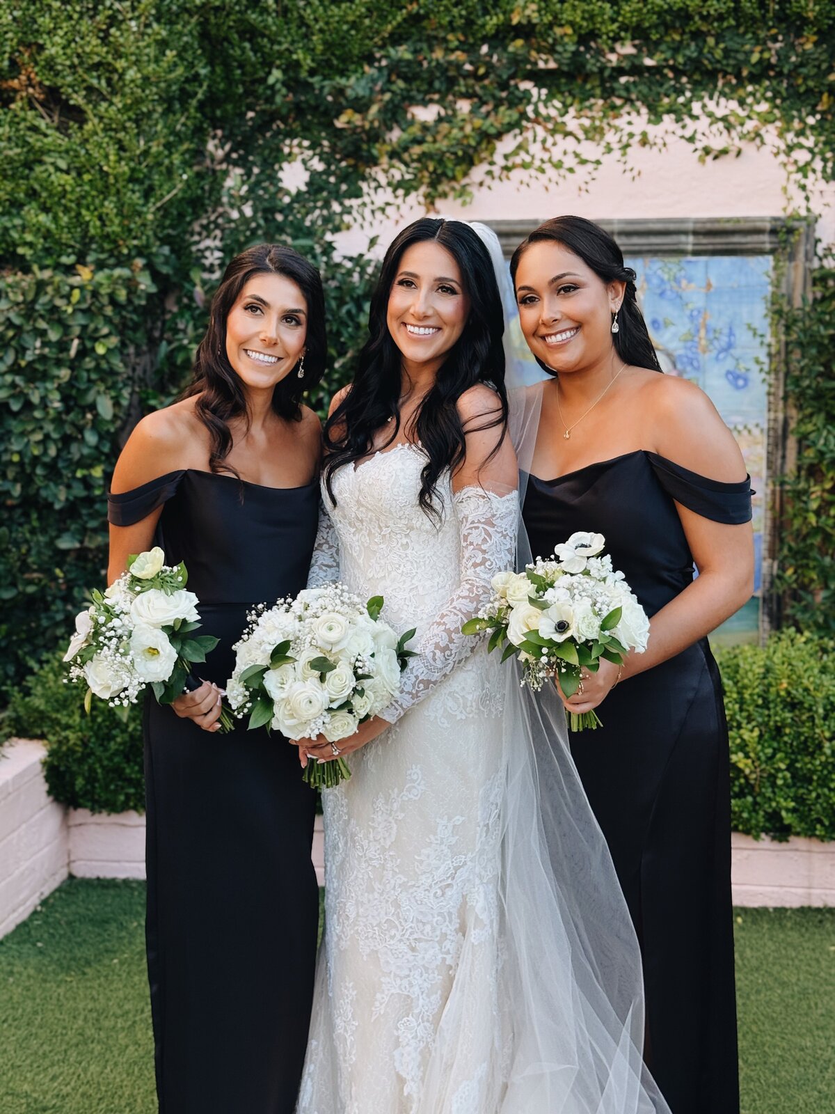 Bride smiling for a portrait with her sisters and maid of honors in the gardens of La Valencia.
