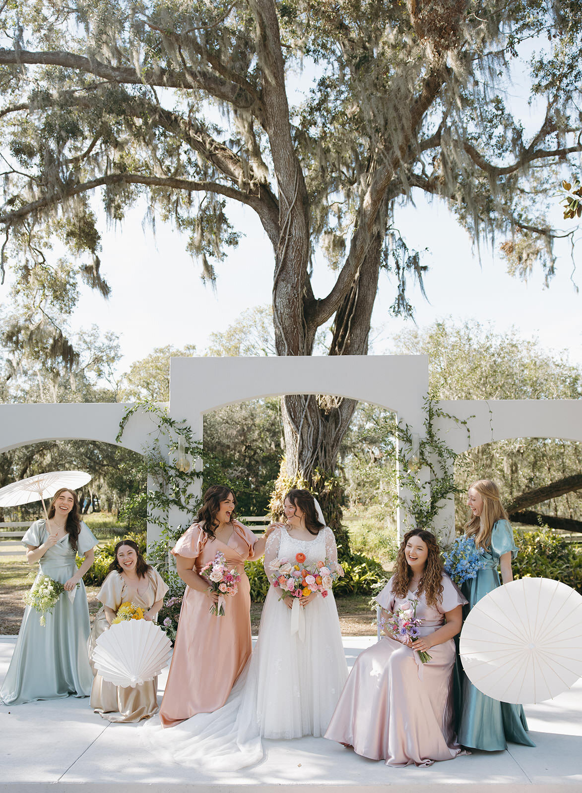 Bridesmaids cheering under oak trees at Uliana Estate, a joyful Lakeland Florida wedding venue.