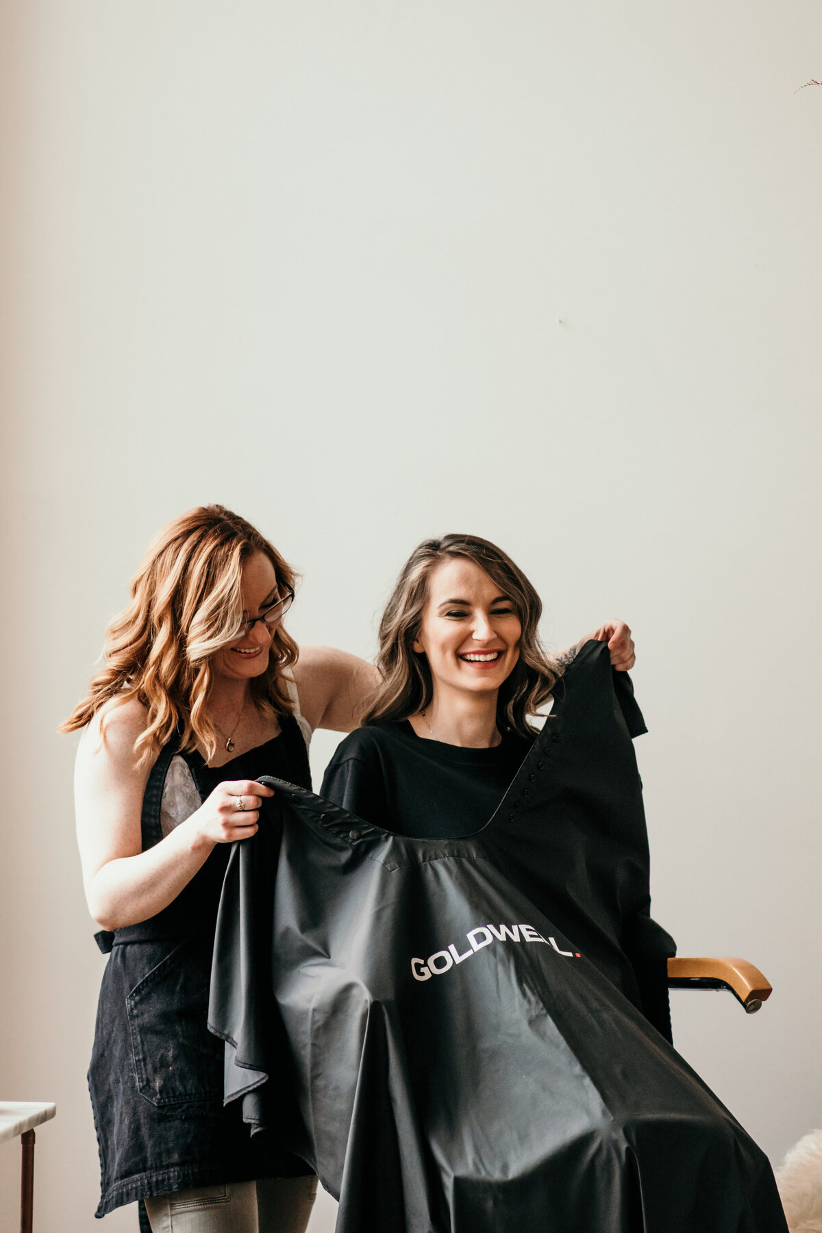 hairstylist puts cape on client