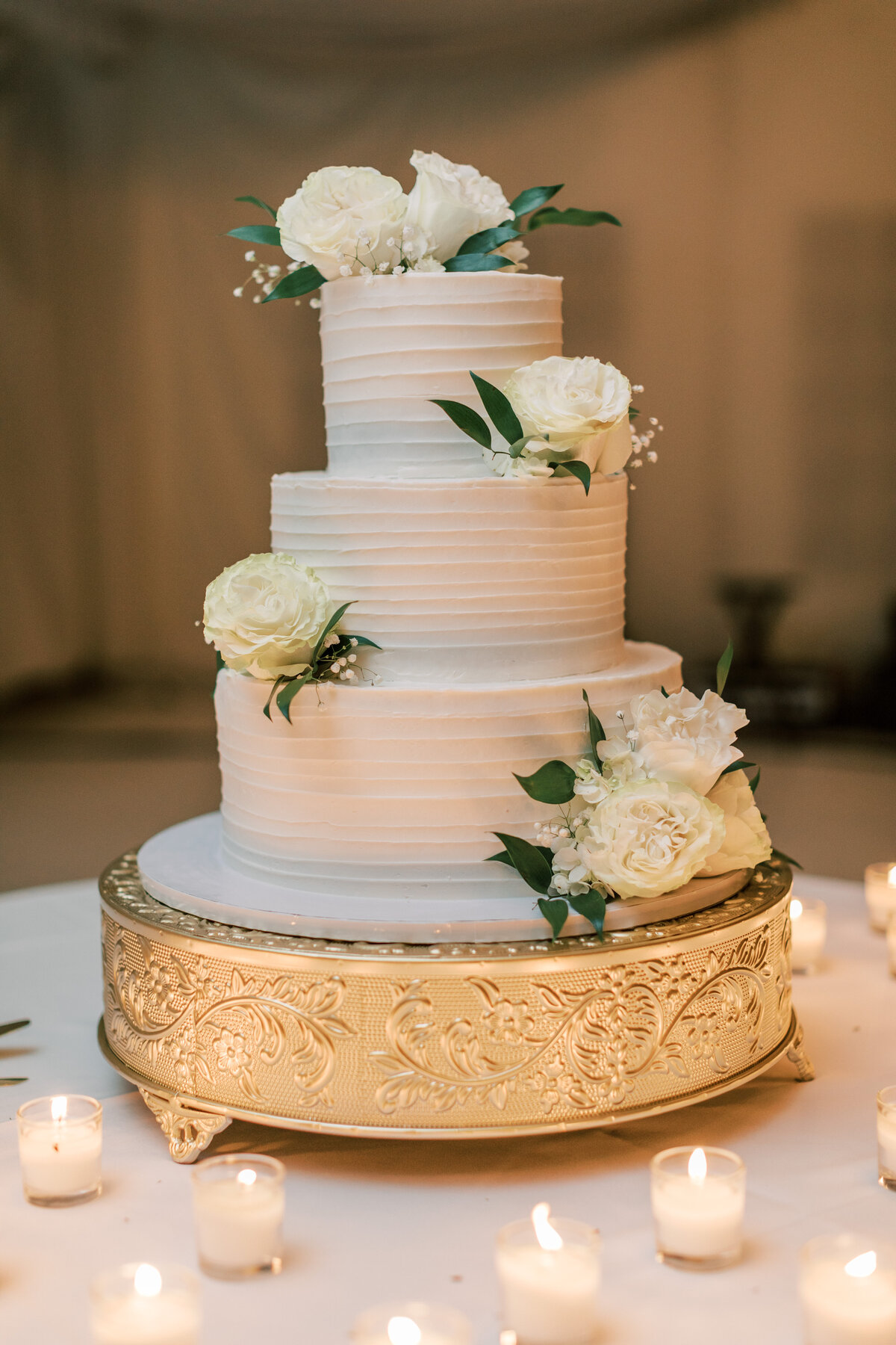 A wedding cake sits on a gold cake stand.