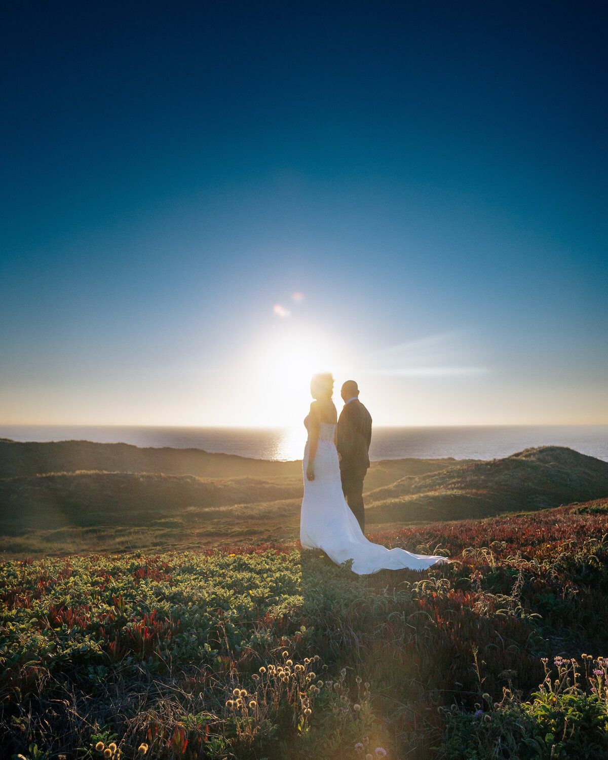 Bride and groom pose at sunset