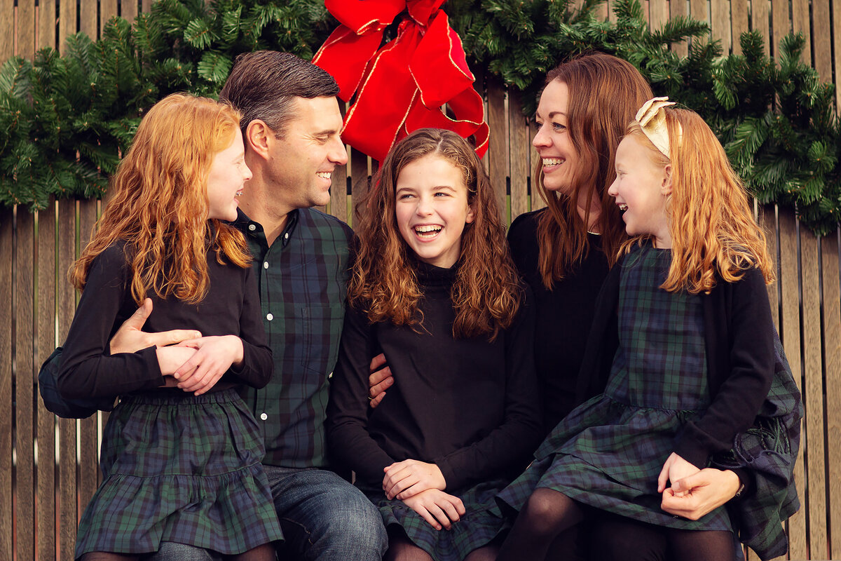 Three sisters with curly, red hair laughing with their parents.