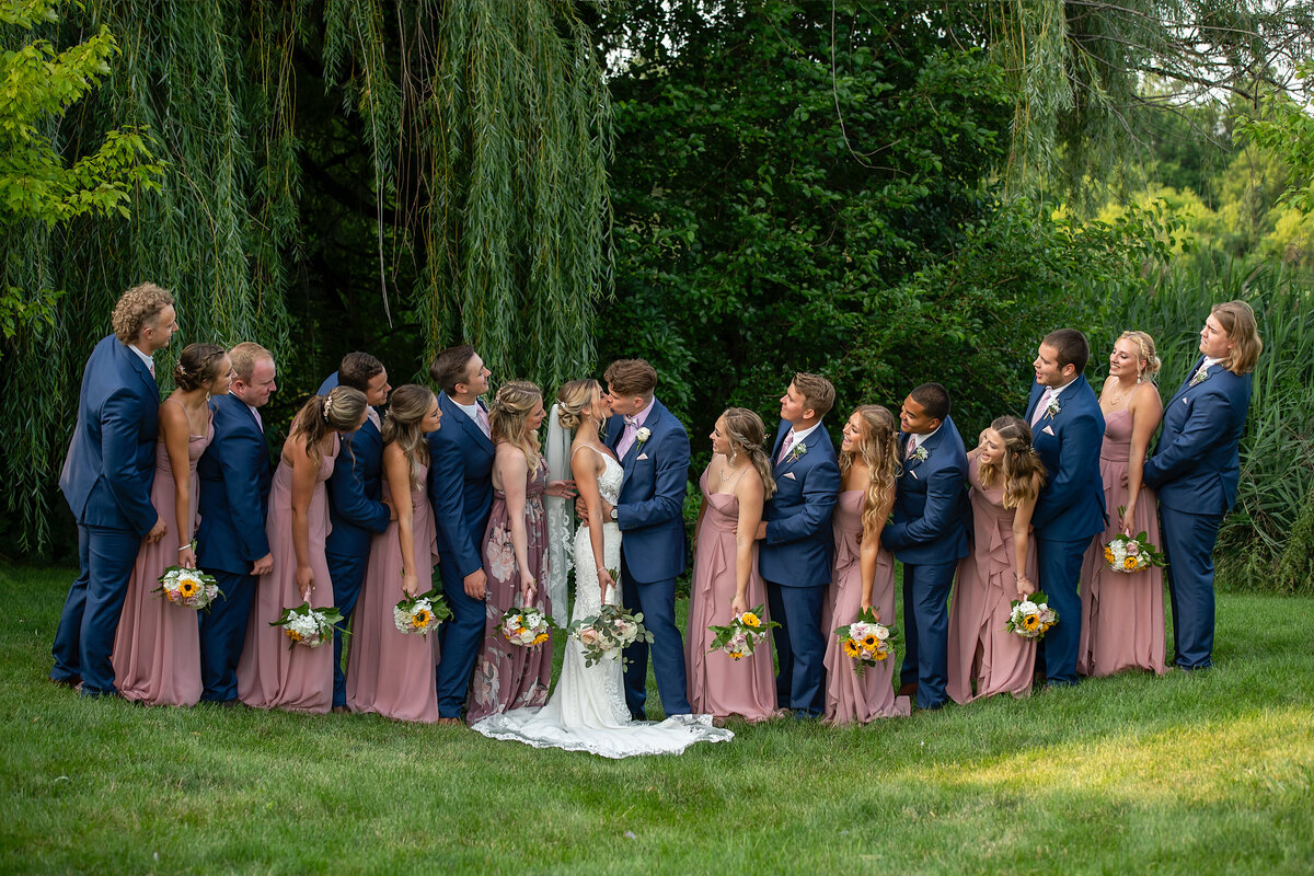 bridesmaids and groomsmen are looking at the bride and groom kissing each other