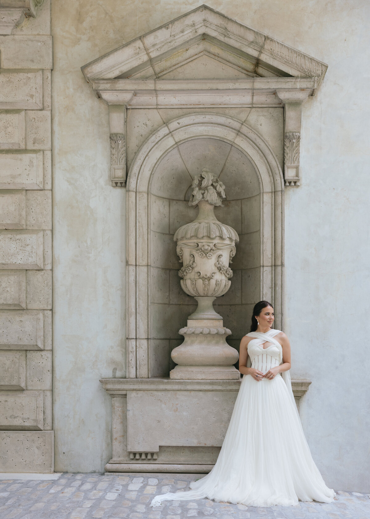 Elegant bride in a flowing white gown posing in front of a historic stone fountain at the Swan House in Atlanta, captured by Kayt Zirkle Photography in a timeless editorial wedding style.