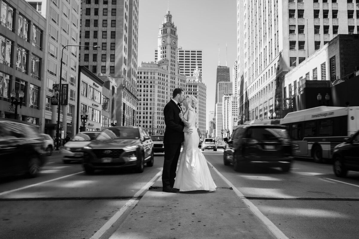 Cars rush past bride and groom while they stand in the middle of Michigan Ave.