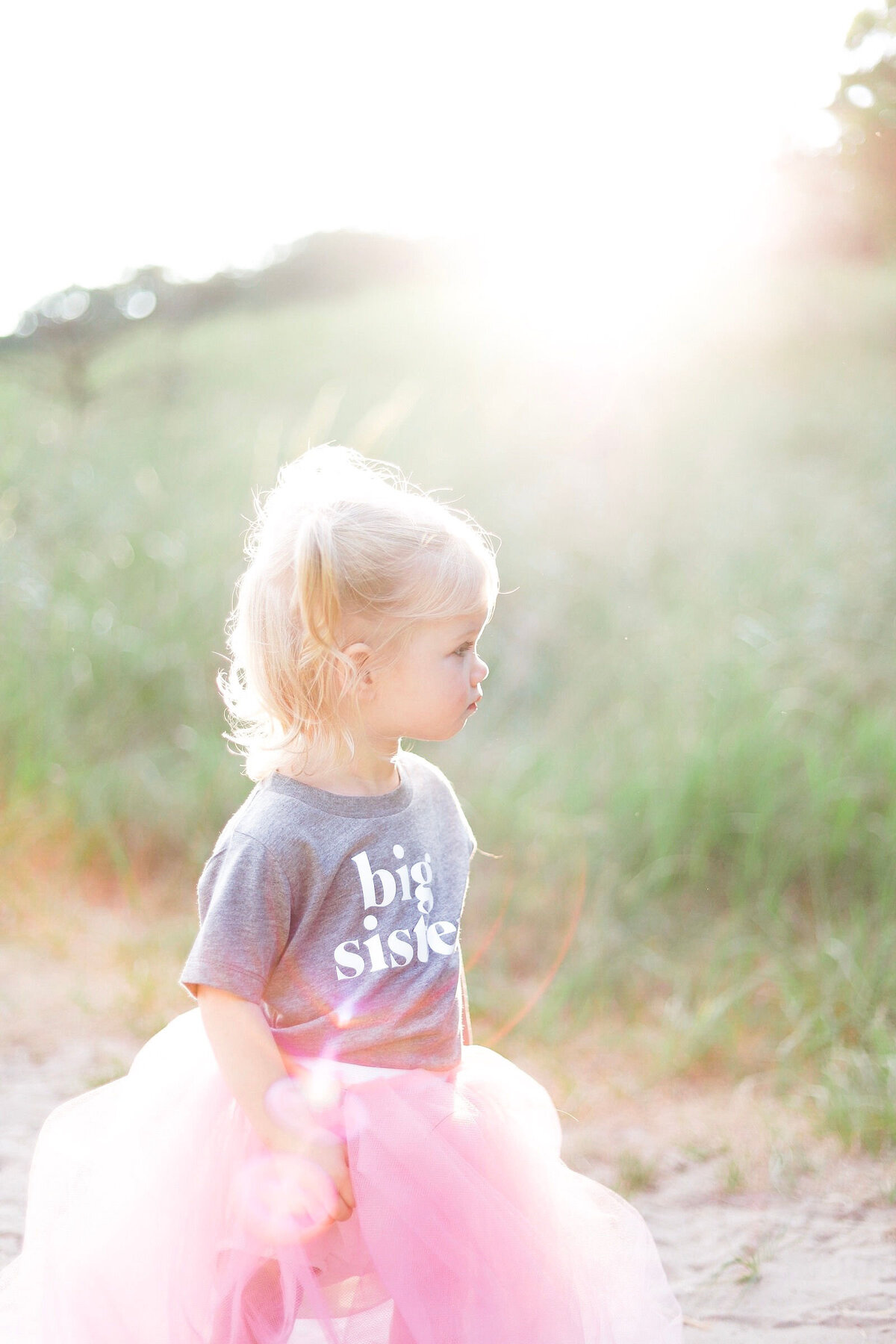 little girl with a big sister shirt standing in the sunlight