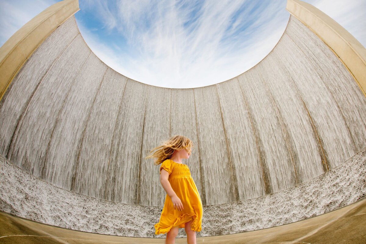 dramatic photo of a girl in a yellow dress with water behind her
