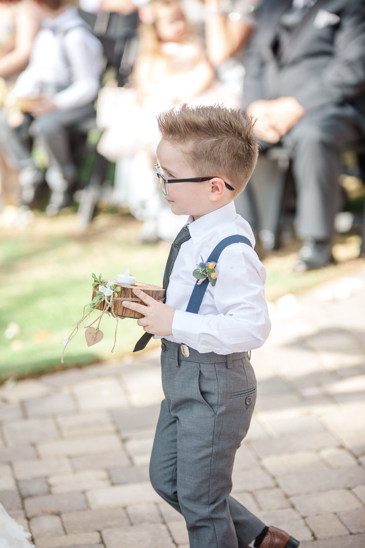 ring bearer in suspenders carries box to groom at Hayes Hollow at Hidden Falls in Spring Branch Texas