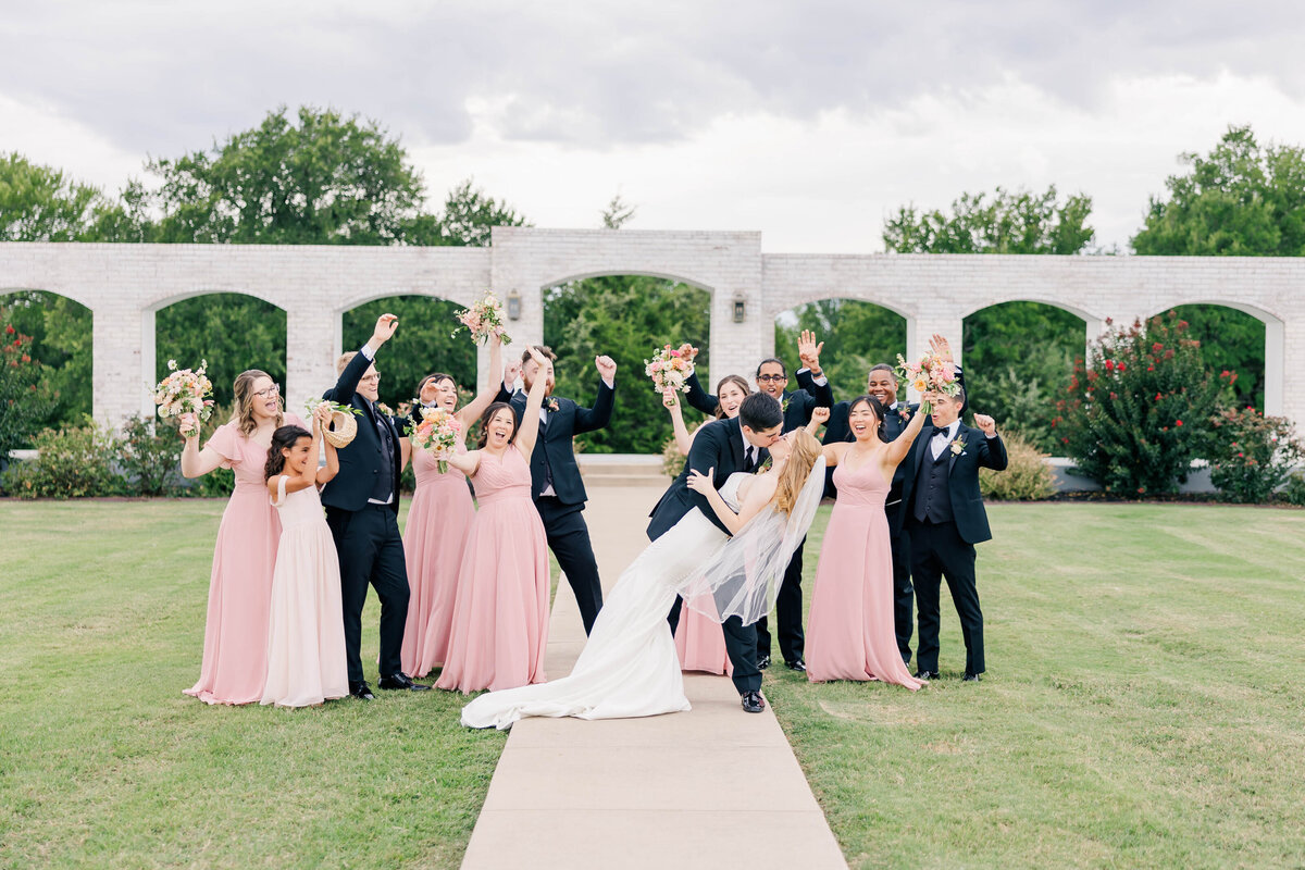 bridal party photo celebrating their friends kissing on their wedding day